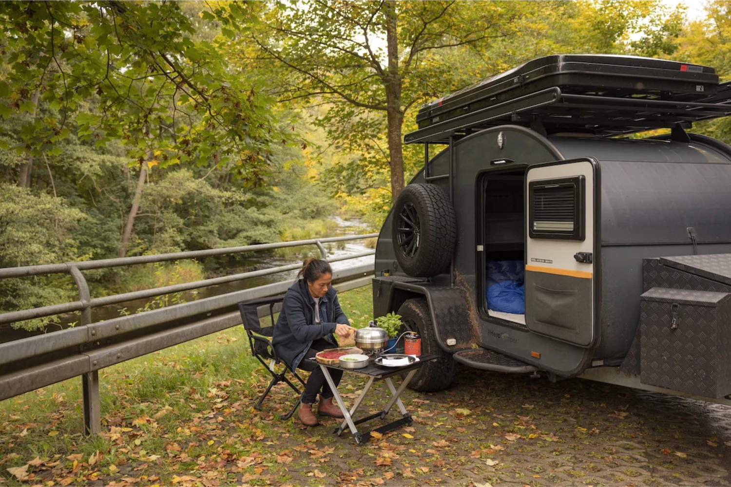 Frau kocht neben HeroCamper minimalistisch