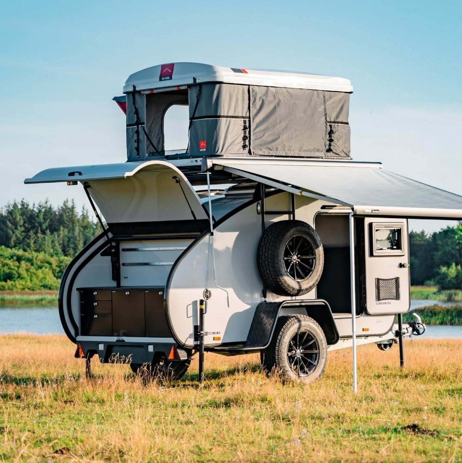 HeroCamper Mini-Wohnwagen mit Markise und Auto-Dachzelt. Küchenzeile als Outdoor Campingküche.