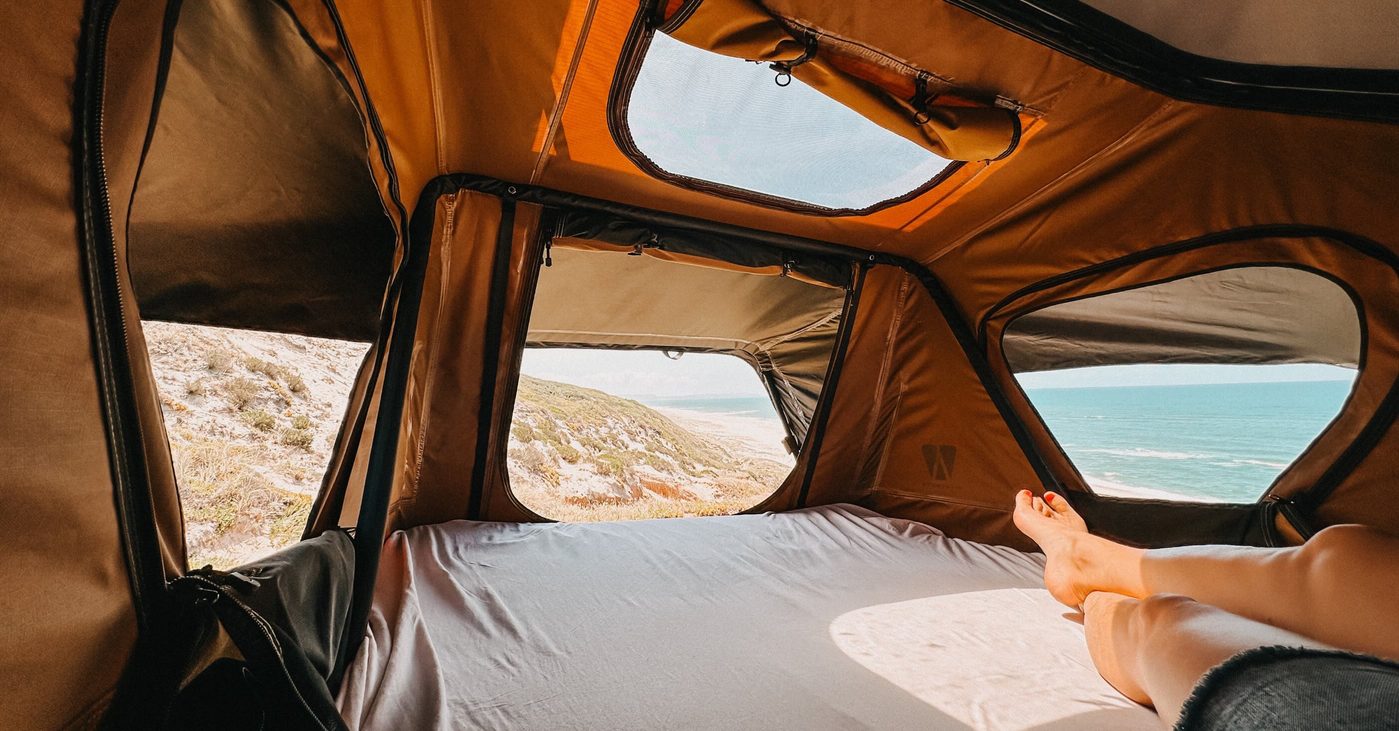 Auto-Dachzelt Innenansicht mit geöffneten Fenstern und Blick auf Meer und Strand
